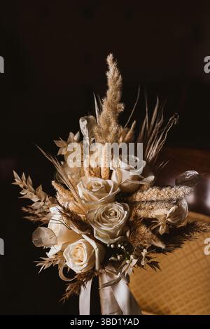 Elegante bouquet con rose bianche e un mix di erbe e foglie essiccate, creando una composizione floreale rustica ma sofisticata. Ideale per matrimoni Foto Stock