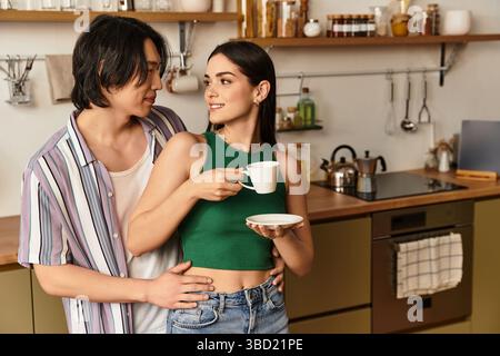Una coppia si gode un momento dolce insieme nella loro accogliente cucina, gustando il caffè. Foto Stock