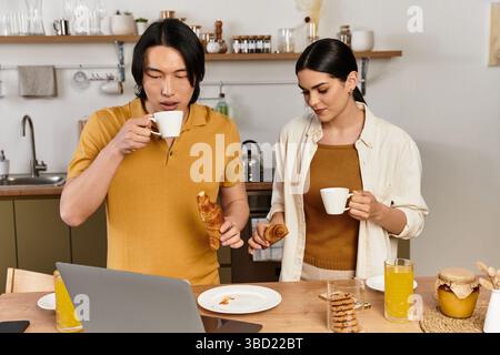 Una coppia condivide una deliziosa colazione con caffè e croissant nella loro calda cucina. Foto Stock