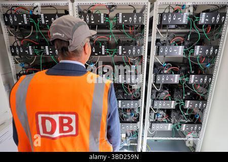 22 maggio 2025, Sassonia, Lipsia: Un dipendente di Deutsche Bahn esamina il nuovo sistema di stoccaggio dell'energia elettrica presso la centrale ICE di Lipsia. Il cosiddetto sistema di stoccaggio delle batterie di seconda durata è costituito da vecchie batterie per auto elettriche che vengono caricate utilizzando il sistema solare dell'azienda. Il sistema solare e il sistema di stoccaggio delle batterie potrebbero coprire circa un quarto del fabbisogno elettrico dell'impianto DI Lipsia. Il progetto pilota risparmierebbe circa 85.000 euro in costi energetici ogni anno. Il passo successivo consiste nell'dotare l'impianto di manutenzione di Kassel di un sistema di stoccaggio delle batterie di seconda durata. Foto: Jan Woit Foto Stock
