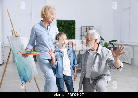 I nonni e la loro nipote dipingono insieme a casa Foto Stock