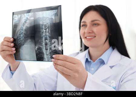 Medico sorridente che esamina la scansione RM del collo in clinica Foto Stock