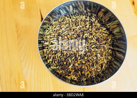 Spezie Panch Phoron in un recipiente in acciaio inox. Panch Phoron ha cinque spezie. Semi di cumino, semi di nigella, semi di finocchio, semi di sedano selvatico e fieno greco Foto Stock