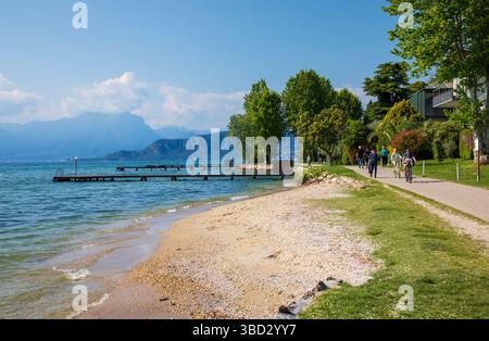 LAZISE, ITALIA - 10 maggio 2025: Bellissima pista ciclabile tra Bardolino e Lazise Foto Stock