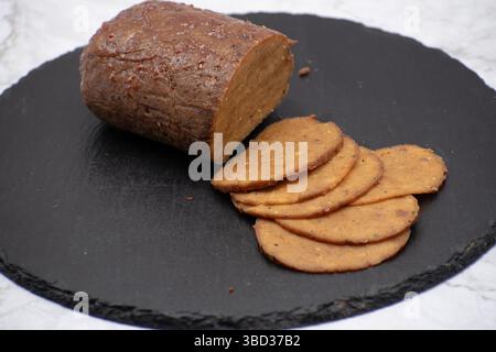 Seitan: Alternativa di carne vegana fatta con glutine di frumento vitale, tagliata su tavola di ardesia Foto Stock