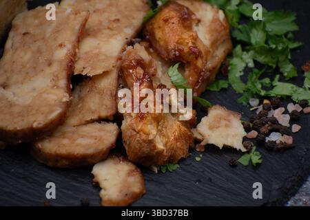 Seitan: Alternativa di carne vegana fatta con glutine di frumento vitale, tagliata su tavola di ardesia Foto Stock