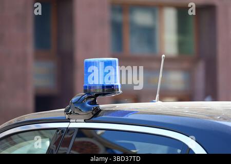 Luce blu lampeggiante e antenne di comunicazione su un'auto governativa in una strada cittadina. Nozione di autorità, vantaggi e privilegi dei funzionari Foto Stock