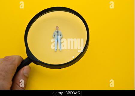 guardando una figurina in miniatura con una lente di ingrandimento Foto Stock