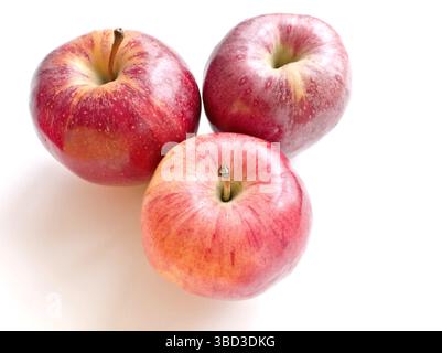 Tre mele sono sedute su uno sfondo bianco. Le mele sono rosse e lucide. Sono disposti in una forma triangolare Foto Stock
