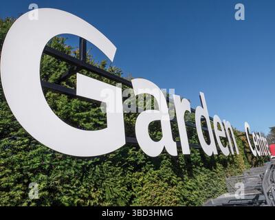 Insegna bianca grafica Garden Centre, con il sole primaverile e i carrelli delle piante in primo piano. Surrey Regno Unito Foto Stock