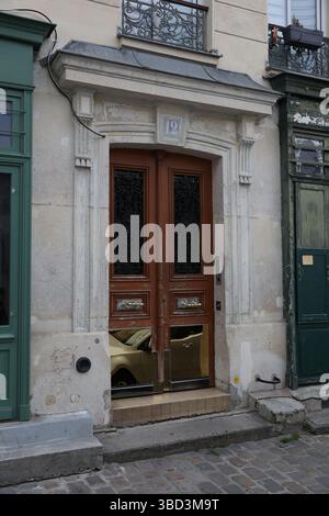 Un ingresso splendidamente realizzato presenta porte in legno con intricati dettagli in ferro battuto nero nei pannelli superiori. Foto Stock