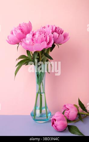 Bellissimo mazzo di peonie rosa fresche in vaso su sfondo rosa. Foto verticale Foto Stock
