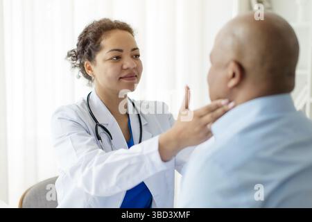 Medico femminile di colore concentrata che controlla i linfonodi dell'uomo paziente maturo Foto Stock