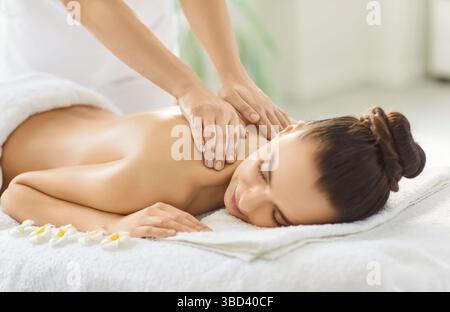 Immagine ritagliata di una massaggiatrice sconosciuta che fa un massaggio alla schiena per una donna cliente Foto Stock