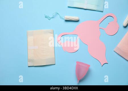 Composizione con utero di carta e prodotti per l'igiene femminile su sfondo colorato Foto Stock