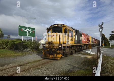 HOKITIKA, NUOVA ZELANDA, 29 AGOSTO 2020: Un treno merci attraversa la strada principale di Hokitika vicino alla rotatoria sulla State Highway 6 Foto Stock