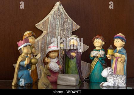 Presepe o nascita del Gesù bambino con figure per bambini e un albero di Natale in legno sullo sfondo. Foto Stock