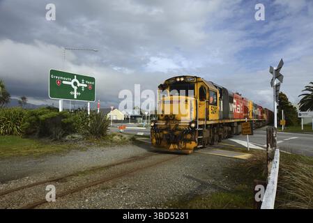 HOKITIKA, NUOVA ZELANDA, 29 AGOSTO 2020: Un treno merci attraversa la strada principale di Hokitika vicino alla rotatoria sulla State Highway 6 Foto Stock