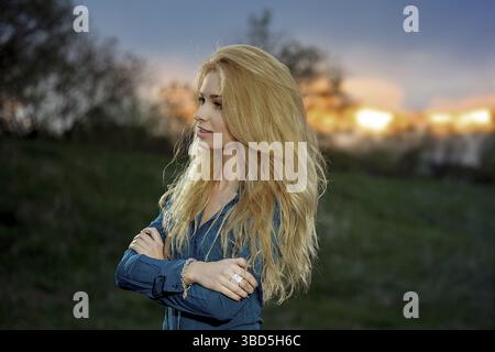 Ritratto all'aperto di una bella donna bionda al tramonto Foto Stock