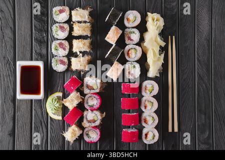 Grande set di rotoli con guarnizione e hashi su piatto di legno scuro Foto Stock