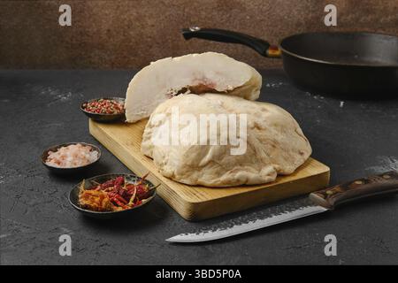 Tagliare la coda di grasso di agnello sul tavolo da cucina con sale e. pepe Foto Stock