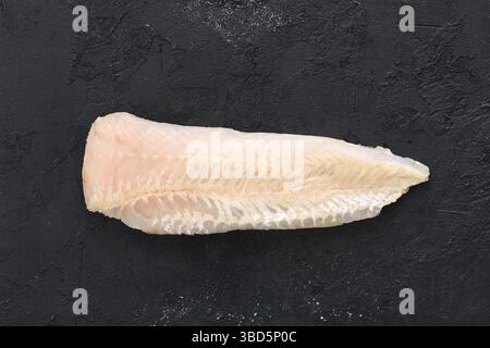 Filetto di nasello di acque basse grezze su sfondo di cemento nero Foto Stock