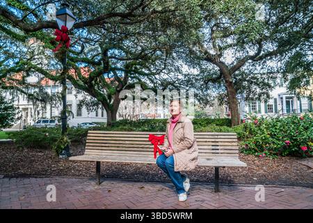 Una bella donna matura seduta su una panchina in un parco cittadino di Savannah, Georgia Foto Stock