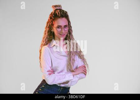 Giovane donna con dreadlock incrociate le mani sul petto Foto Stock