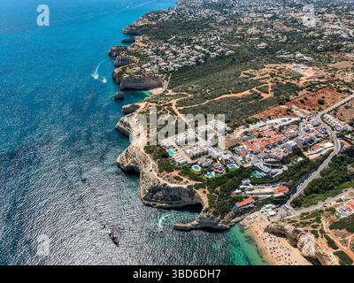 Aspre scogliere dell'Algarve con area boschiva e acque turchesi dall'alto Foto Stock