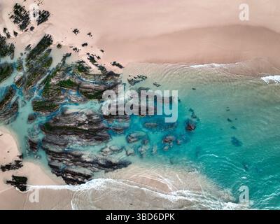 Immagine aerea della costa rocciosa e del mare turchese poco profondo vicino alla spiaggia sabbiosa Foto Stock