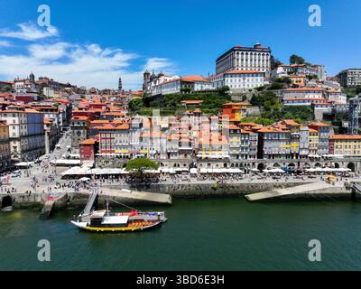 Porto, Portogallo - 12 maggio 2024: Vista sul lungomare di Ribeira con case vivaci e barca ormeggiata Foto Stock