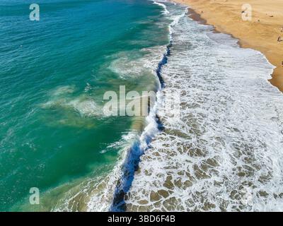 Vista aerea che mostra motivi di schiuma marina dalle onde che si infrangono in acque poco profonde Foto Stock