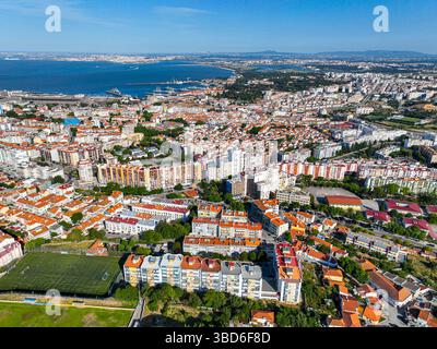 Almada, Portogallo - 12 maggio 2024: Ripide scogliere di Almada che incontrano una baia sabbiosa con vecchie mura del forte e banchine sul lungomare Foto Stock