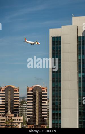 Almada, Portogallo - 12 maggio 2024: Aerei commerciali TAP in avvicinamento all'aeroporto passando davanti a edifici moderni Foto Stock