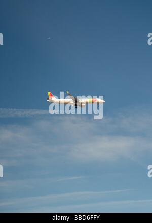 Almada, Portogallo - 12 maggio 2024: Aereo commerciale TAP Air Portugal che vola sotto un cielo azzurro Foto Stock