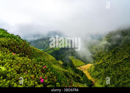 Nebbia che si snoda su lussureggianti colline e valli viste da Boca do Inferno a São Miguel Foto Stock