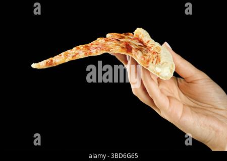 La mano regge una fetta di pizza al formaggio su sfondo nero Foto Stock