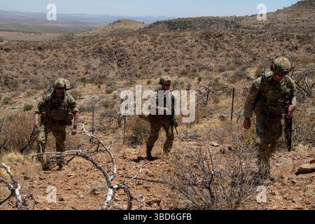 Soldati statunitensi, assegnati alla 76th Engineer Company, 41st Engineer Battalion, con Joint Task Force–Southern Border, scalano il terreno roccioso lungo il confine meridionale durante una missione di deposito dei segni della New Mexico National Defense area (NMNDA) nei pressi di Antelope Wells, New Mexico, 20 maggio 2025. Sotto la direzione del Northern Command degli Stati Uniti, la Joint Task Force–Southern Border allinea gli sforzi per sigillare il confine meridionale e respingere le attività illegali ed è responsabile di operazioni su larga scala, agili e di tutti i domini, che consentiranno operazioni DoD più efficaci ed efficienti. (Foto U.S. Army di SPC. Anjelica Foto Stock