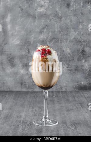 Bicchiere di caffè freddo con panna montata e ciliegia su sfondo grigio scuro Foto Stock