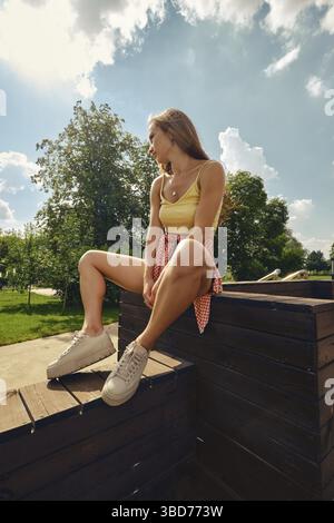 Giovane donna bella siede su pavimento di legno Foto Stock