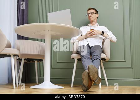 Uomo di mezza età che si rilassa davanti a un notebook a casa Foto Stock