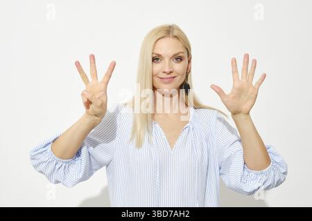 Una donna bionda attraente mostra otto dita. Contare con le dita Foto Stock