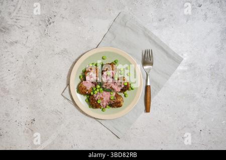 Vista dall'alto delle polpette con piselli verdi freschi e salsa di mirtilli su sfondo di pietra grigia Foto Stock