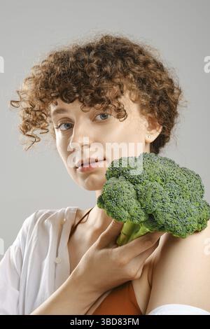 Una giovane donna carina tiene i broccoli in mano. Concetto di mangiare sano Foto Stock