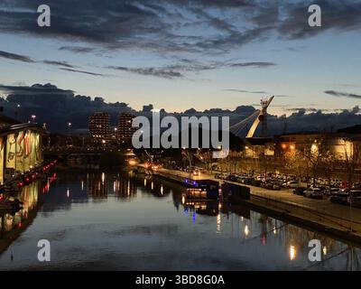 Vista panoramica serale del Ponte Risorgimento a Pescara, con edifici illuminati che si riflettono sul tranquillo fiume sotto un cielo spettacolare Foto Stock