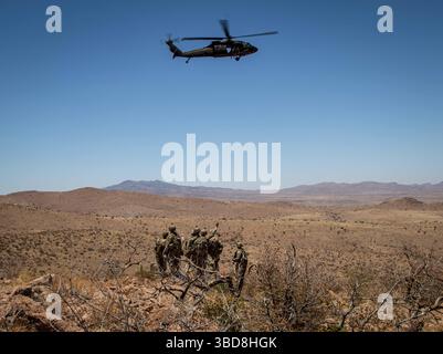 I soldati statunitensi con la 76th Engineer Company, assegnati alla Joint Task Force-Southern Border, salutano un elicottero UH-60 Black Hawk dell'esercito statunitense assegnato alla 1st Combat Aviation Brigade, 1st Infantry Division, durante una missione aerea per consegnare i segnali della New Mexico National Defense area (NMNDA) vicino ad Antelope Wells, New Mexico, 20 maggio 2025. I materiali sono stati forniti dalla consegna aerea a causa del terreno austero che limitava le manovre a terra. Sotto la direzione del Northern Command degli Stati Uniti, la Joint Task Force–Southern Border allinea gli sforzi per sigillare il confine meridionale e respingere le attività illegali ed è responsabile della completa scal Foto Stock