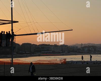 Persone che si stagliano ammirando un bellissimo tramonto sulla spiaggia di Pescara da un trabocco, una tradizionale piattaforma di pesca, in Abruzzo, Italia Foto Stock