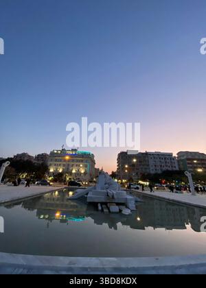 Vista urbana al tramonto del paesaggio urbano di Pescara che si riflette sull'acqua con il monumento, in largo Mediterraneo, Abruzzo, Italia Foto Stock