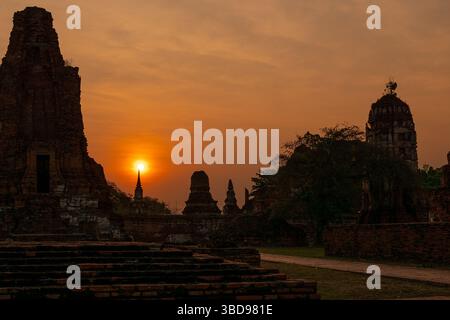 Ayutthaya, Tailandia - 19 marzo 2025: Veduta di Wat Mahathat con il sole che sorge di mattina sullo sfondo ad Ayutthaya, Tailandia. Foto Stock