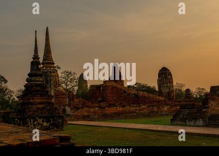 Ayutthaya, Tailandia - 19 marzo 2025: Veduta di Wat Mahathat con il sole che sorge di mattina sullo sfondo ad Ayutthaya, Tailandia. Foto Stock
